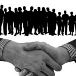 握手する手と人物のシルエット